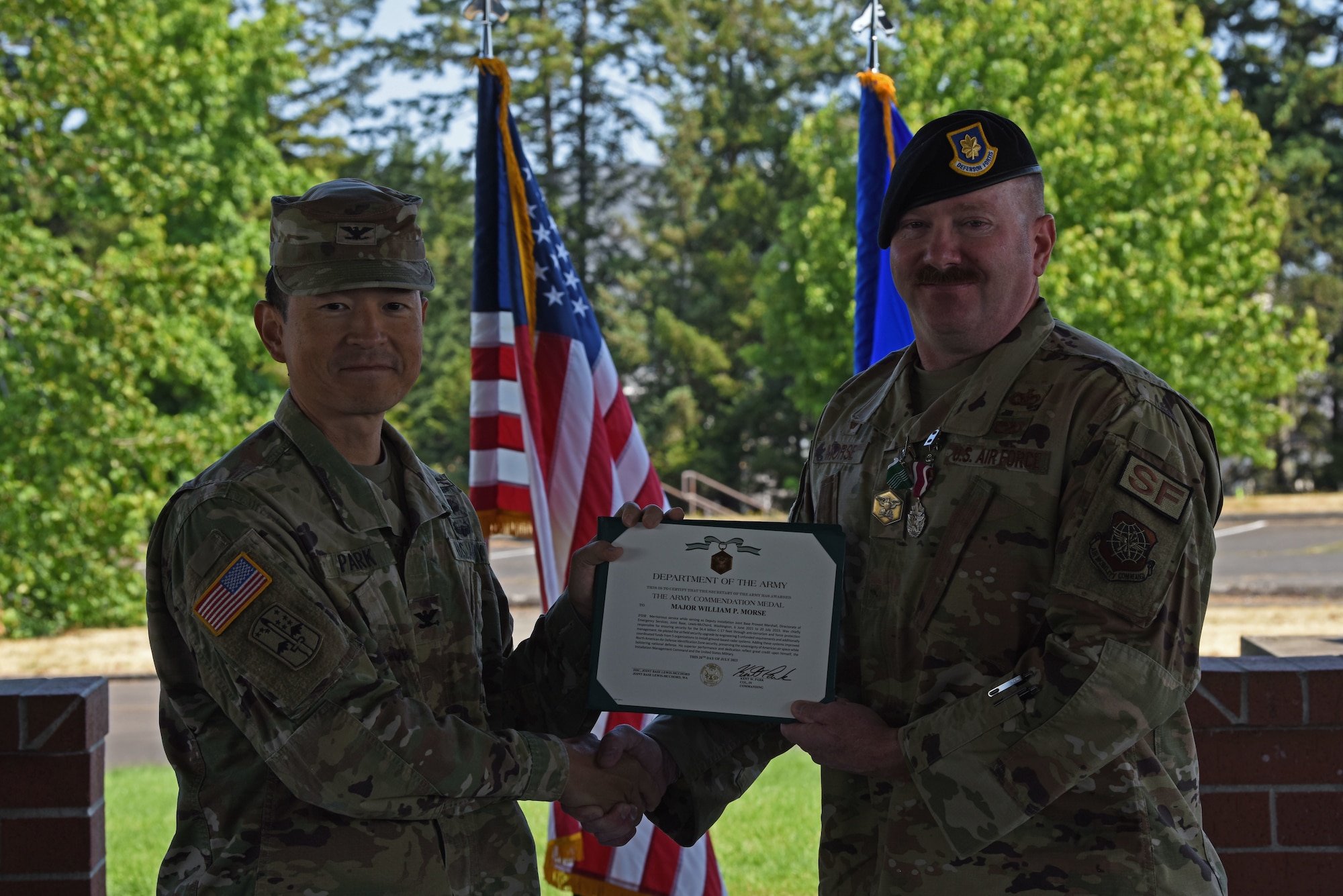 U.S. Army Col. Kent Park, Joint Base Lewis-McChord garrison commander, left, presents Maj. William Morse, outgoing 627th Security Forces commander, with an Army Commendation Medal at the 627th SFS change of command ceremony at Joint Base Lewis-McChord, Washington, July 20, 2023. Morse served as commander of the 627th SFS for two years and under his command, the squadron received the 2022 Air Mobility Command Security Forces Squadron of the Year award. (U.S. Air Force photo by Staff Sgt. Zoe Thacker)