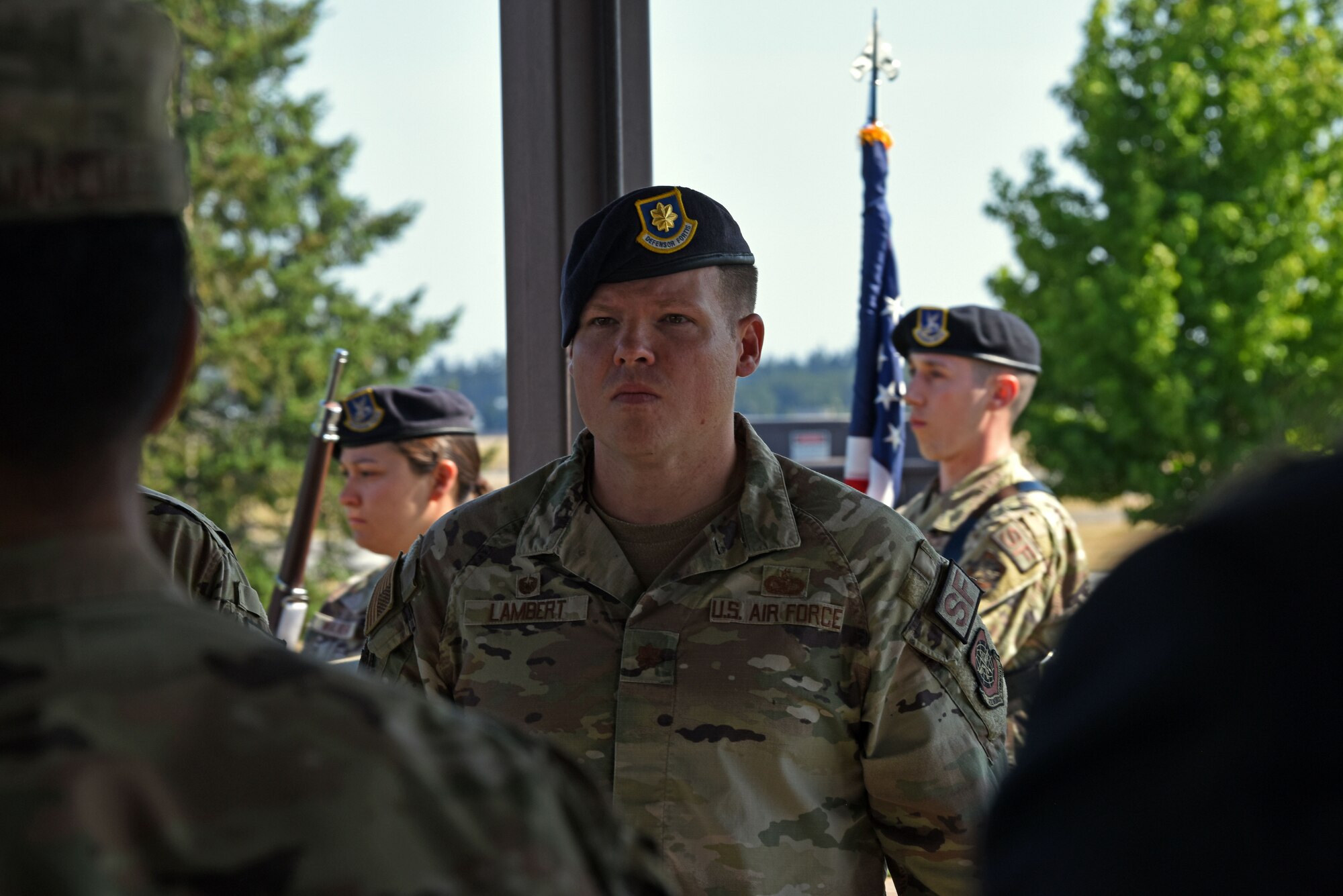 U.S. Air Force Maj. Daniel Lambert, incoming 627th Security Forces Squadron commander, stands at attention while 627th SFS Airmen present the colors during a change of command ceremony at Joint Base Lewis-McChord, Washington, July 20, 2023. The mission of the 627th SFS is to defend the McChord Field flightline, execute Phoenix Raven flyaway security operations in support of U.S. Transportation Command, and lead combat arms training for JBLM Airmen. (U.S. Air Force photo by Staff Sgt. Zoe Thacker)