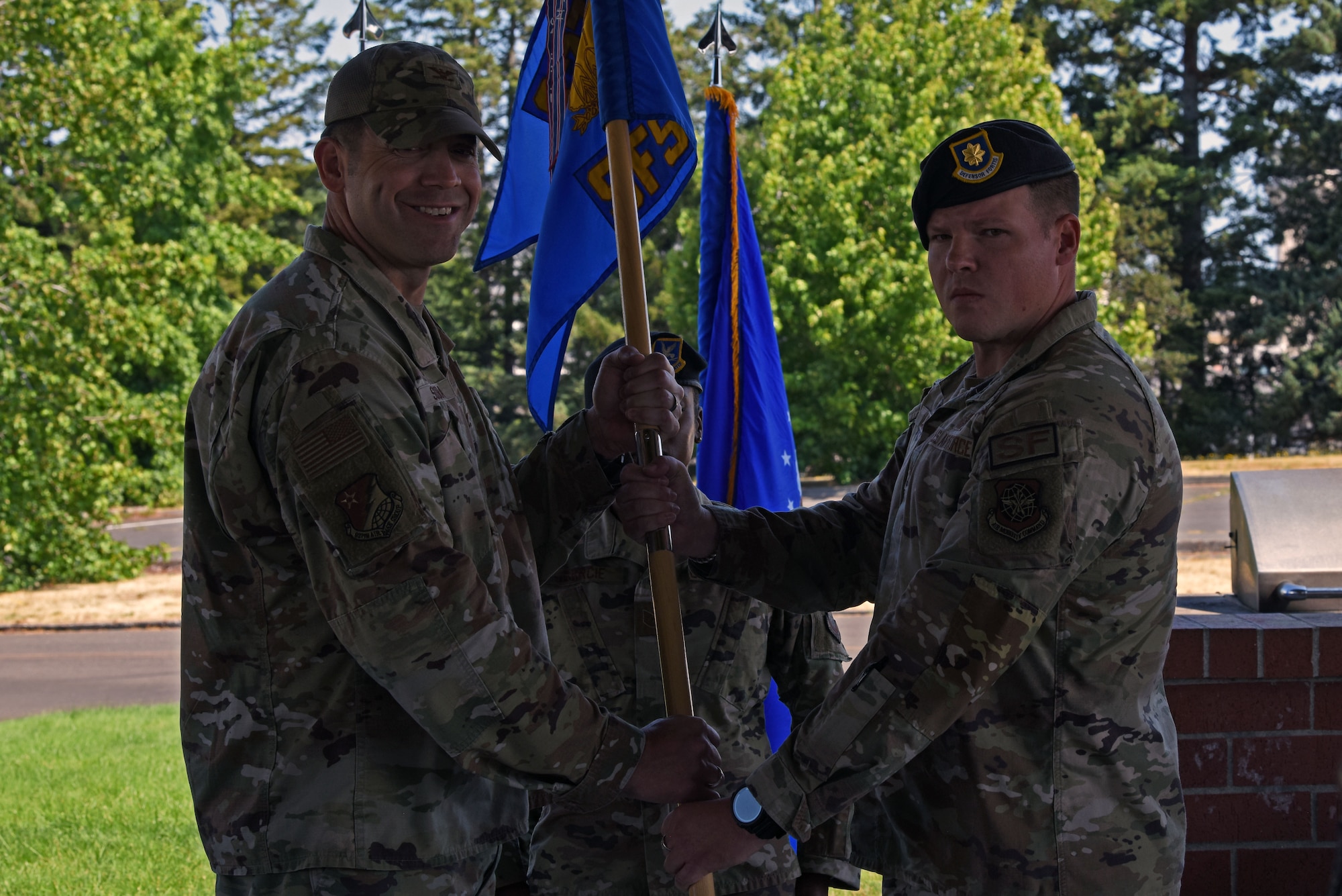 U.S. Air Force Col. Brandon Sokora, 627th Air Base Group commander, left, presents Maj. Daniel Lambert, incoming 627th Security Forces Squadron commander, with the 627th SFS guidon during a change of command ceremony at Joint Base Lewis-McChord, Washington, July 20, 2023. The mission of the 627th SFS is to defend the McChord Field flightline, execute Phoenix Raven flyaway security operations in support of U.S. Transportation Command, and lead combat arms training for JBLM Airmen. (U.S. Air Force photo by Staff Sgt. Zoe Thacker)