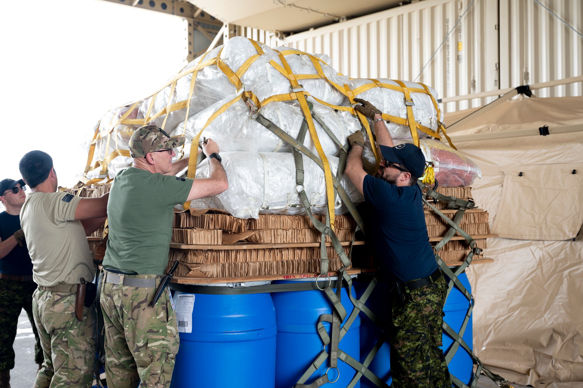 Members of the Royal New Zealand Air Force and Royal Canadian Air Force work together to unpack cargo during Mobility Guardian 23 at Andersen Air Force Base, Guam, July 8, 2023. 3,000 personnel directly supported the large-scale mobility exercise, which provided the maneuver of more than 15,000 U.S. and international forces associated with other exercises across the Indo-Pacific held in the same timeframe. (U.S. Air Force photo by Staff Sgt. Malissa Lott)