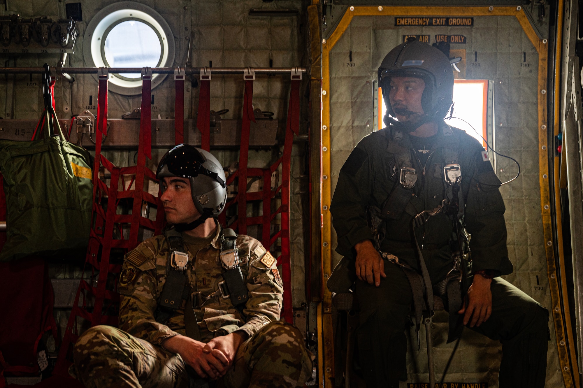 A Japan Air Self-Defense Force C-130H Hercules loadmaster (right)  assigned to the 401st Tactical Airlift Squadron, and U.S. Air Force 2nd Lt. Rayne Jones, a Battlespace Engineer assigned to the 31st Combat Training Squadron, sit in a C-130H during a coaltion airdrop mission over Tinian, July 12, 2023, for Mobility Guardian 23. MG23 is an opportunity to train alongside our Allies and partners to demonstrate interoperability and bolster our collective ability to support a free and open Indo-Pacific. (U.S. Air Force photo by Staff Sgt. Devin M. Rumbaugh) (Portions of this photo are blurred for security reasons)