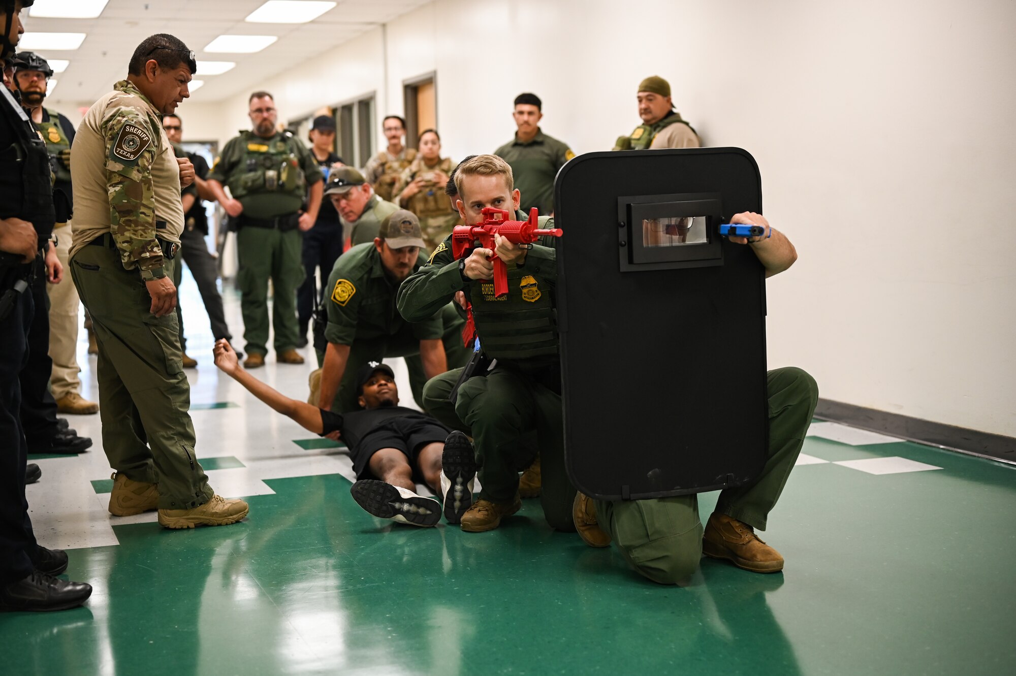 Customs and border protection (CBP) border patrol officers pull a simulated victim behind a ballistic shield during a training exercise alongside Laughlin Air Force Base's Security Forces at San Felipe Memorial Middle School, Texas, July 12, 2023.