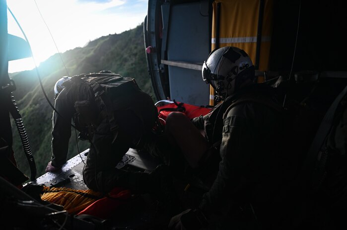 U.S. Navy Petty Officer 1st Class William Bennett, an aviation rescue swimmer assigned to Helicopter Sea Combat Squadron 25, looks for a safe drop zone from a MH-60S Knighthawk on Guam, July 18, 2023. While flying a multinational Maritime Personnel Recovery training event during Mobility Guardian 23, the crew was called to rescue a hiker who had fallen off a mountainside. MG23 is a mobility exercise held across a 3,000-mile area intended to deepen interoperability with U.S. Allies and partners, bolstering the collective ability to support a free and open Indo-Pacific area. (U.S. Air Force photo by Tech. Sgt. Michael Cossaboom)