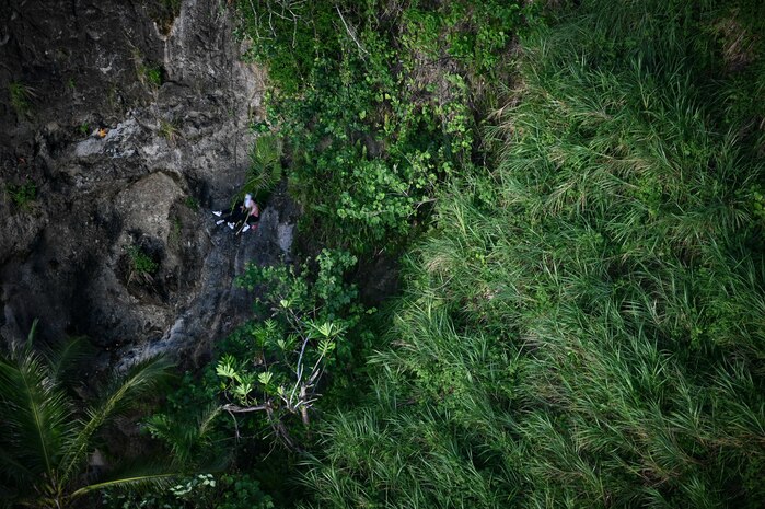 An injured hiker awaits aid from an MH-60S Knighthawk assigned to Helicopter Sea Combat Squadron 25 near Andersen Air Force Base, Guam, July 18, 2023. The crew from HSC 25 was conducting a training mission when they got a call to conduct a search and rescue mission on Guam. (U.S. Air Force photo by Tech. Sgt. Michael Cossaboom) (Faces were blurred for sensitivity reasons)