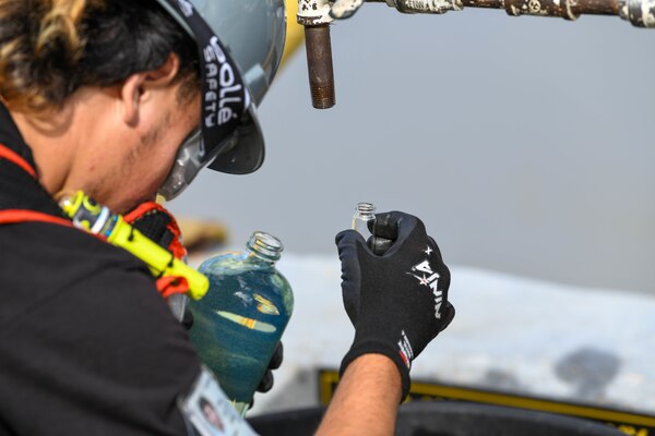 Naval Supply Systems Command Fleet Logistics Center Pearl Harbor employee Lawsen Lee, fuel distribution system worker, observes a sample of F76 marine diesel fuel during an unpacking operation onboard Joint Base Pearl Harbor-Hickam (JBPHH), Hawaii, Oct. 27, 2022. The unpacking operation will remove approximately one million gallons of fuel from three primary fuel pipelines connecting the Red Hill Bulk Fuel Storage Facility (RHBFSF) to fuel points on JBPHH. JTF-RH was established by the Department of Defense to ensure the safe and expeditious defueling of the RHBFSF. (U.S. Marine Corps photo by Cpl. Luke Cohen)