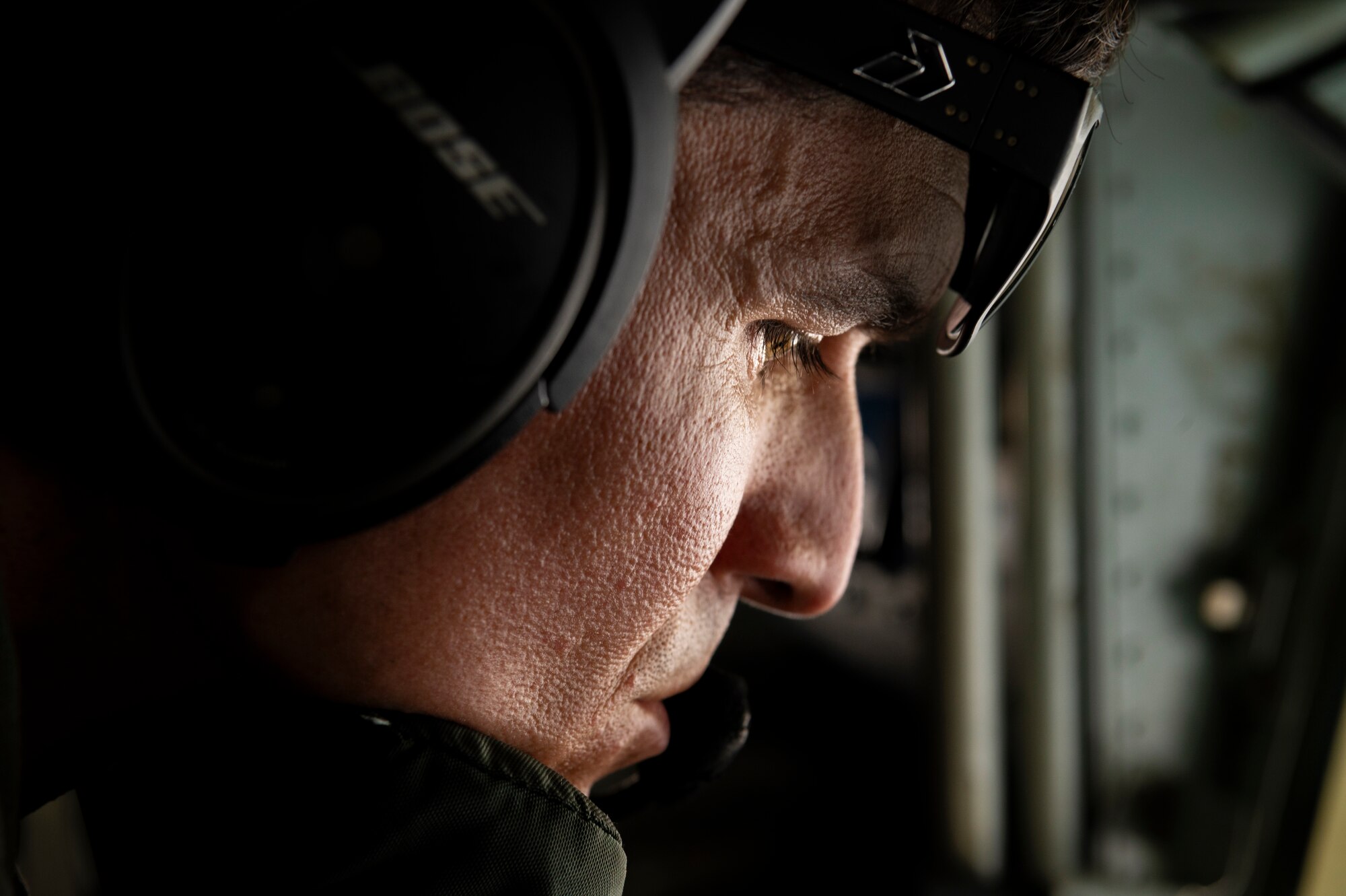 U.S. Air Force Master Sgt. Jason Duckett, 909th Air Refueling Squadron boom operator, looks out of the boom operator's window for receivers while laying in the boom pod of a KC-135 Stratotanker over the Pacific Ocean, July 19, 2023.