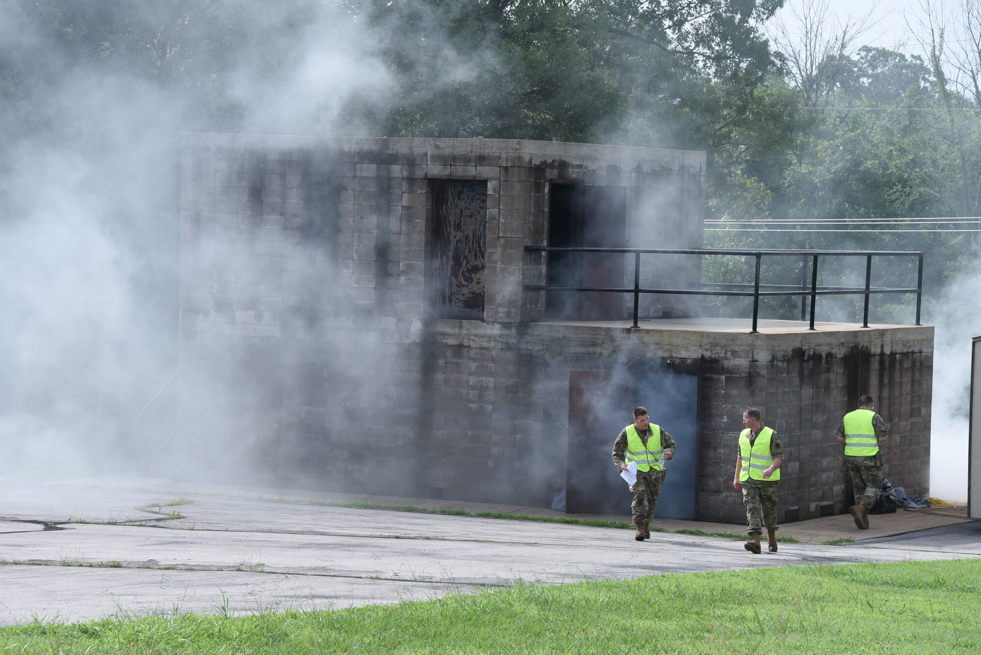 U.S. Air National Guard Master Sgt. Donovan Masters (left), Tech. Sgt. Kyle Sauter (center), and Tech. Sgt. Dylan Hinds (right), 185th Air Refueling Wing tactical combat casualty care instructors, walk around smoking building.