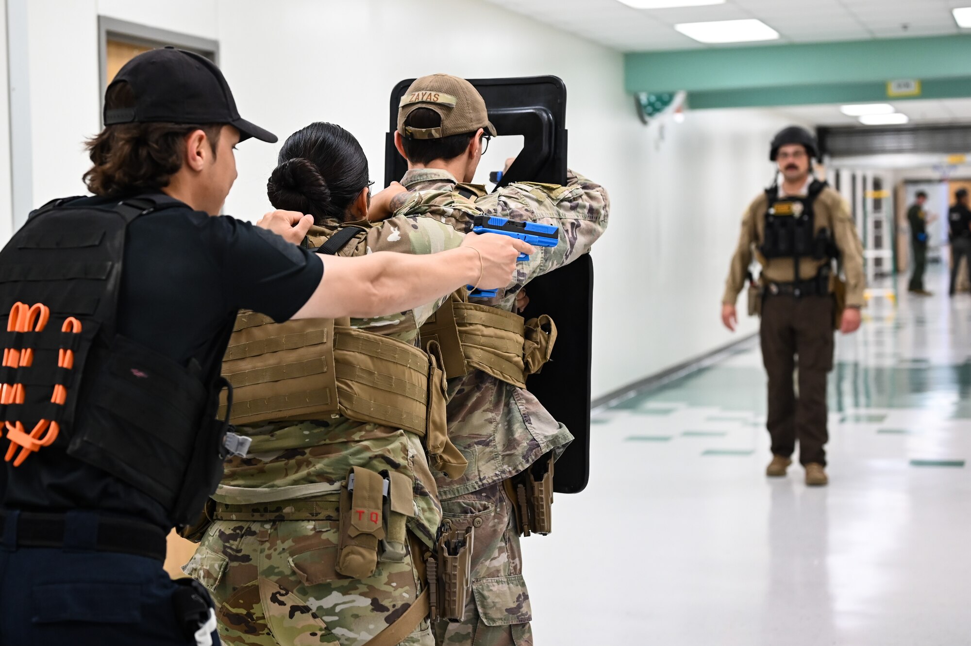 U.S. Air Force Airmen of the 47th Security Forces Squadron aim down sights behind a ballistic shield during a training exercise created by the Val Verde Sheriff's Office at San Felipe Memorial Middle School, Texas, July 12, 2023.