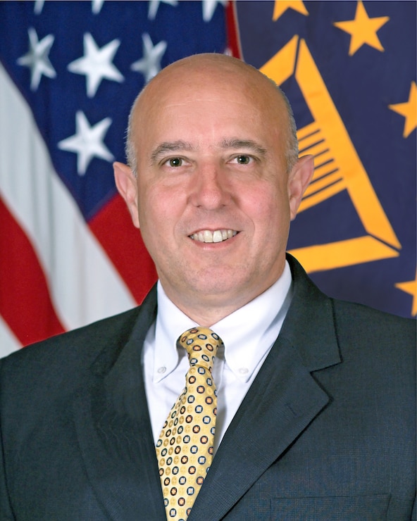 Official portrait of Deputy Director, Washington Headquarters Services, a Department of Defense Field Activity  Robert G. Salesses posing in front of flag display.