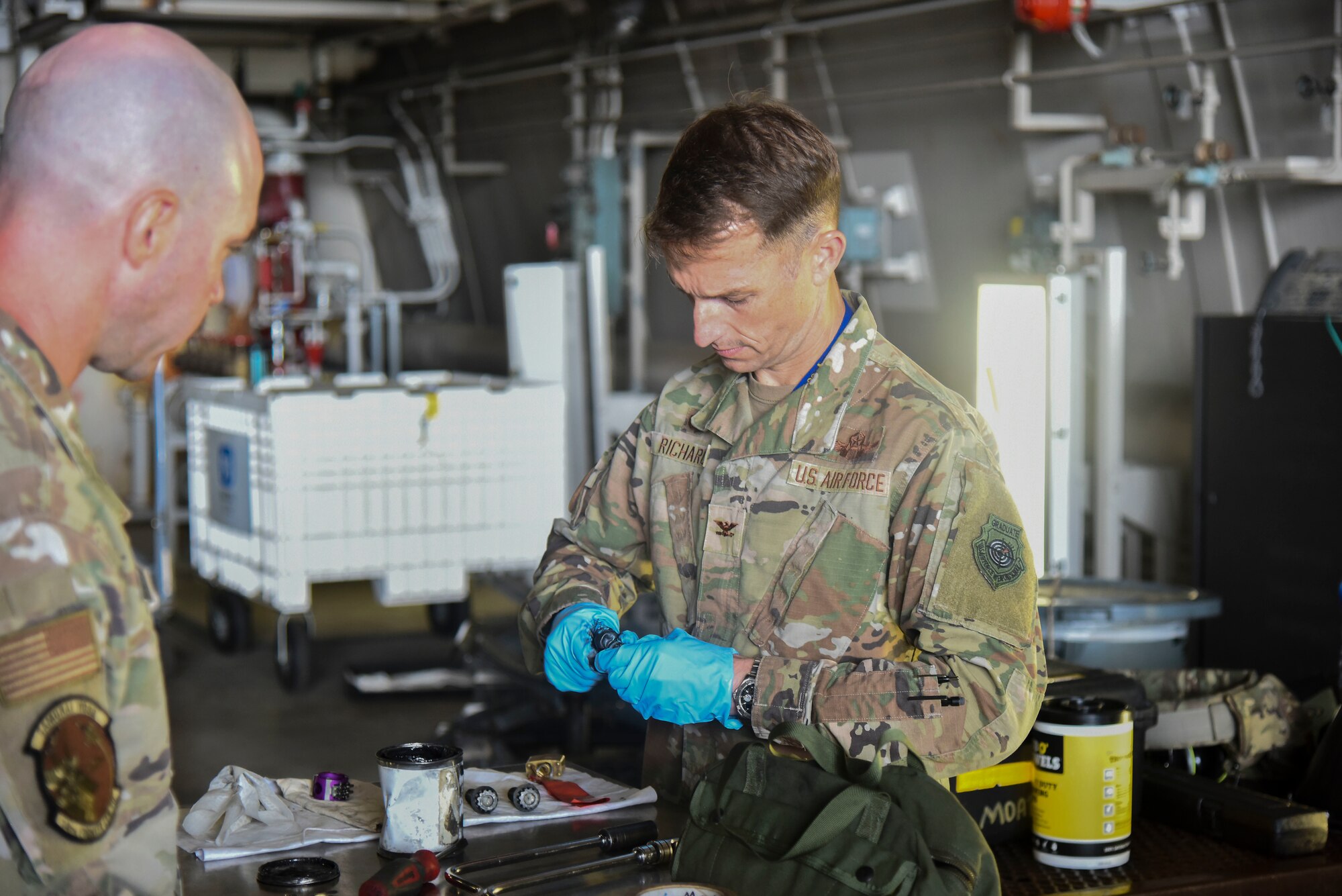 A service member greases a bolt