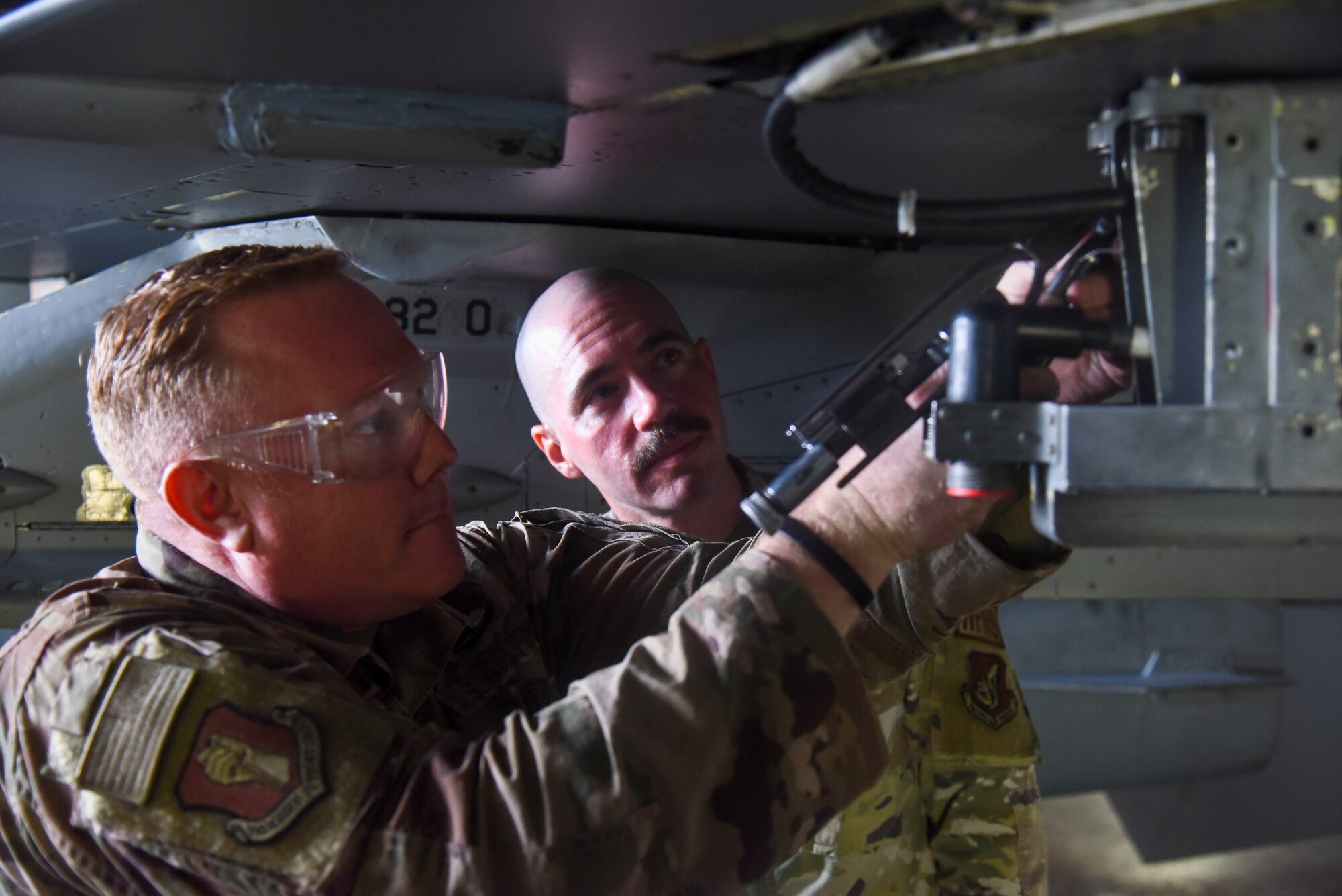 A service member tightens a safety wire to an aircraft