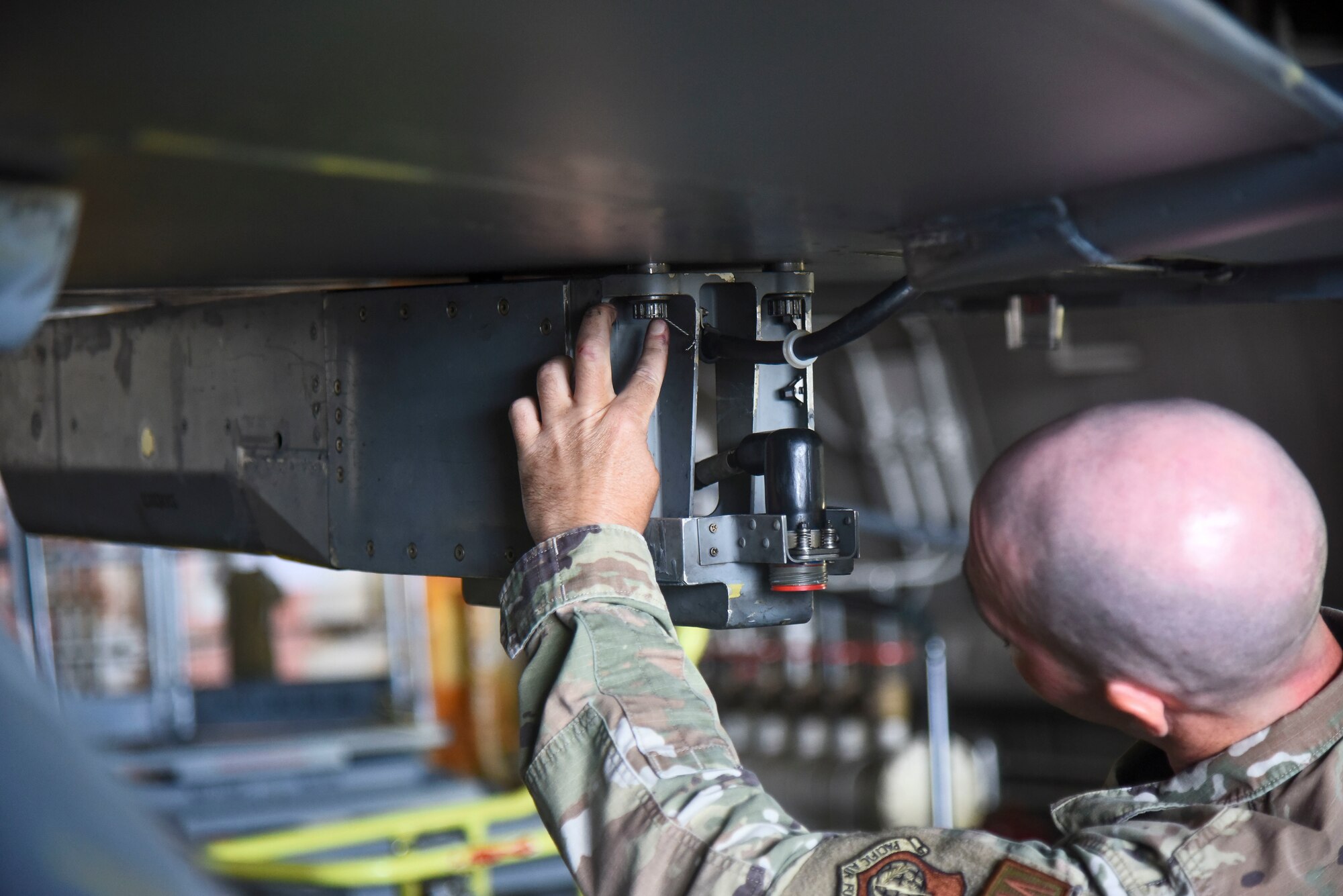 A service member checks a wire attached to an aircraft acting as a safety wire.
