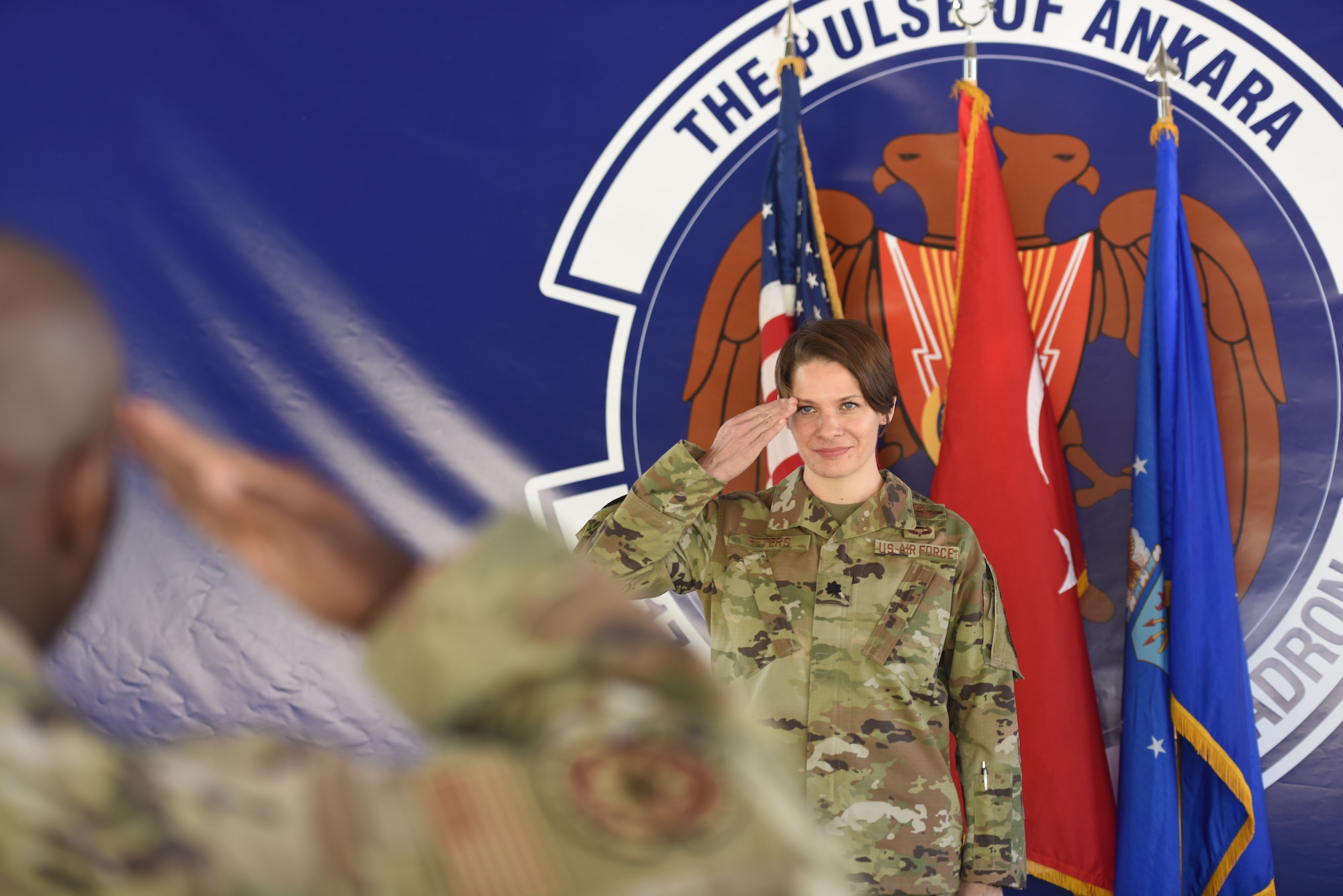 A woman in U.S. Air Force uniform salutes a man in uniform.