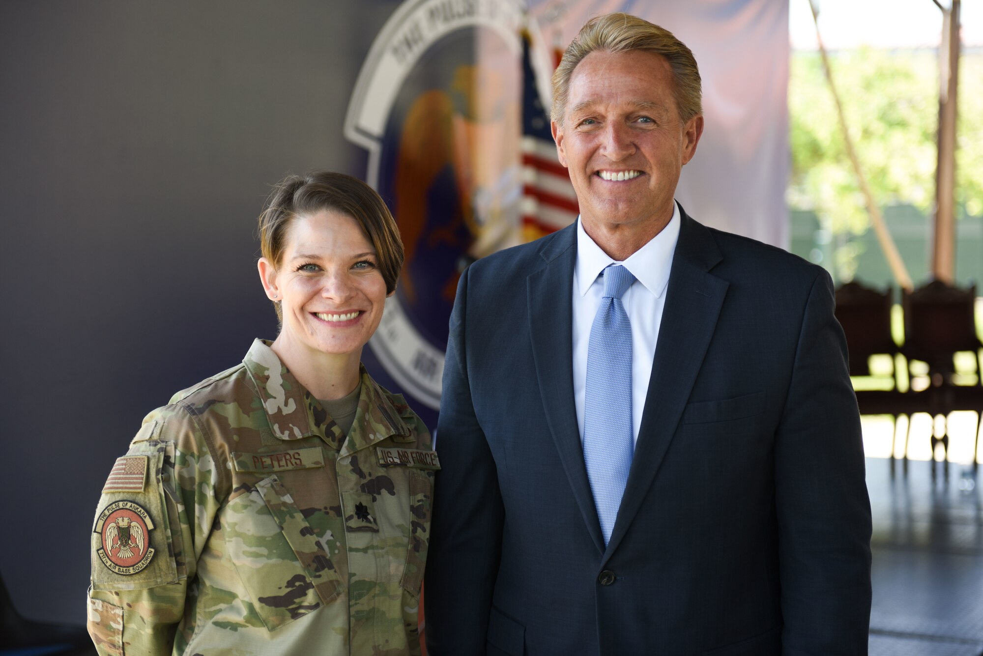 A woman in a U.S. Air Force uniform stands next to a man in a business suit.