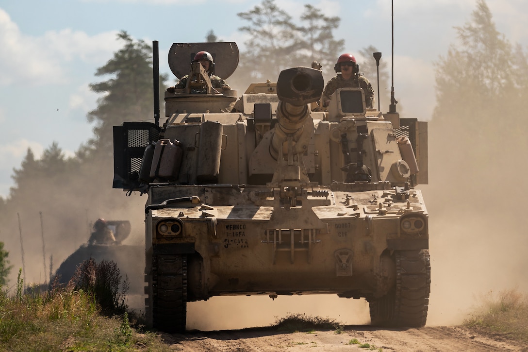 Soldiers drive on a dusty road during a live-fire qualification exercise.