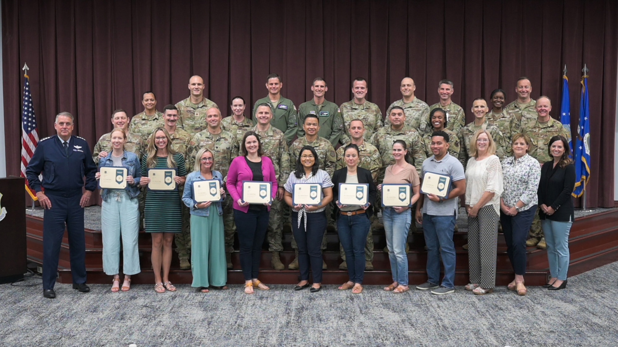 U.S. Air Force Gen. Mike Minihan, Air Mobility Command commander takes a photo with recent graduates from the AMC Squadron Leadership Course at Scott Air Force Base, Illinois, June 30, 2023. After attending approximately 40 hours of training, attendees leave the class with a badge certification showcasing to Airmen, mission partners and industry that they have acquired the experience and resources to lead in a squadron command leadership or spouse role. (U.S. Air Force photo by Rachel Sansano)