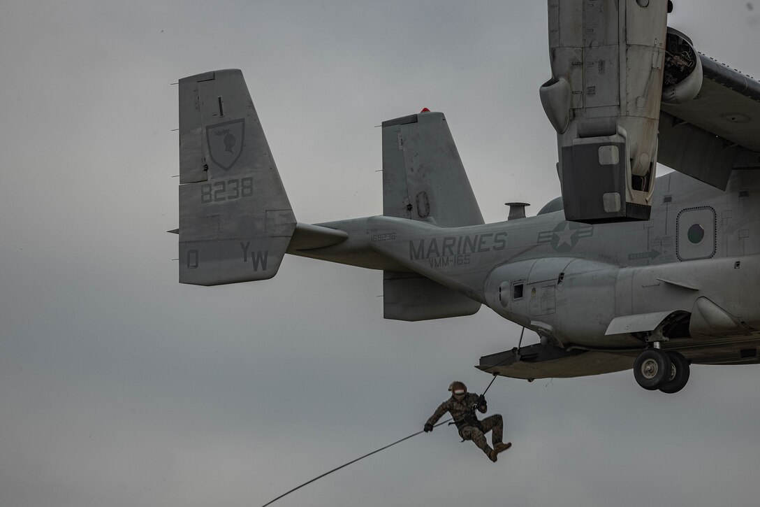 A Marine rappels out of a military aircraft.