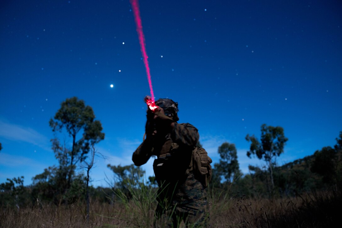 A Marine operates a scope with a red light during a training exercise at dusk.