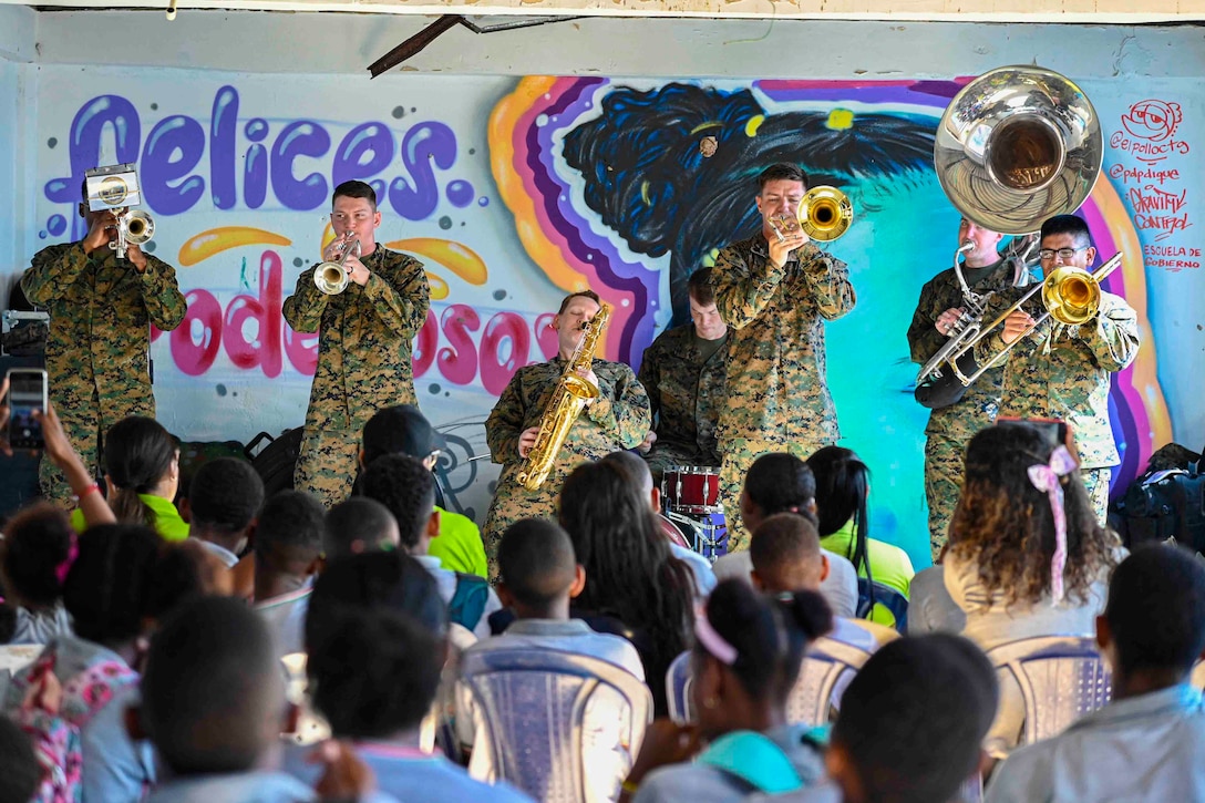 Marines play instruments in front of a crowd.