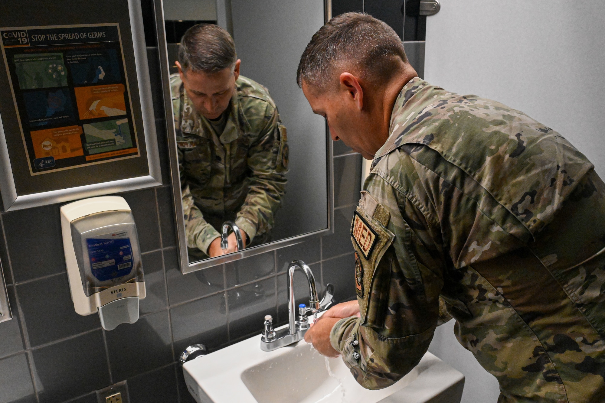 man in uniform washes his hands