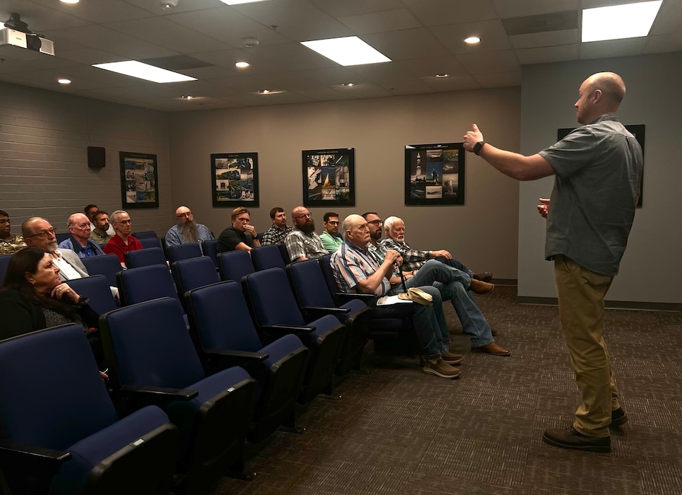 man speaks to group in a theater