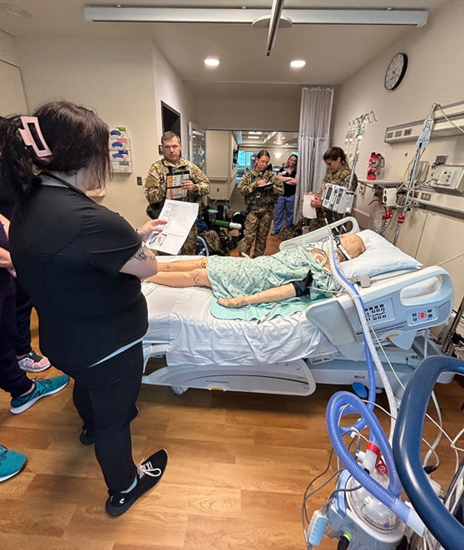 A Wisconsin National Guard Soldier from a medevac asset of the 1st Battalion, 147th Aviation Regiment, briefs Aurora BayCare Medical Center professionals about how patients are transported by UH-60 Black Hawk helicopter during a joint training event June 22.