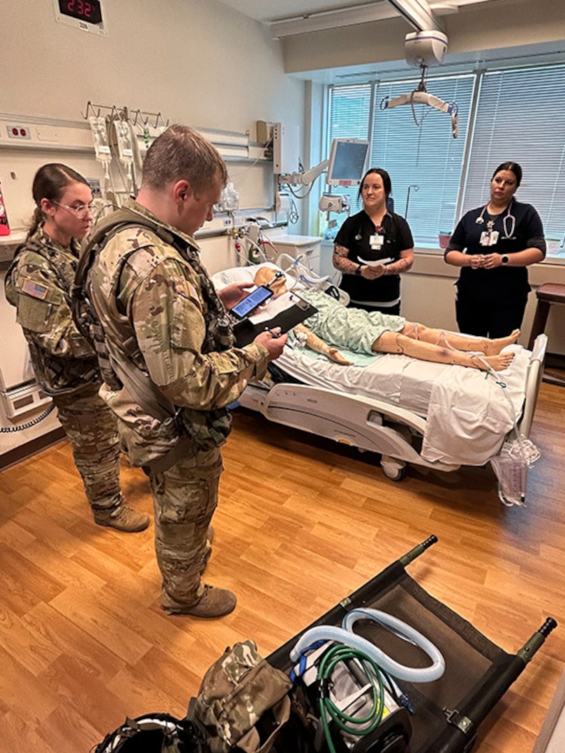 A Wisconsin National Guard Soldier from a medevac asset of the 1st Battalion, 147th Aviation Regiment, briefs Aurora BayCare Medical Center professionals about how patients are transported by UH-60 Black Hawk helicopter during a joint training event June 22.