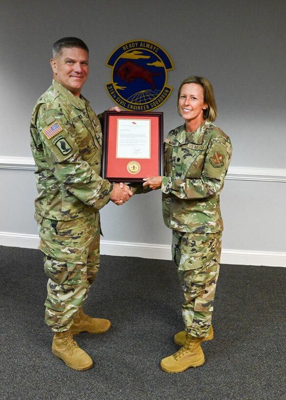 A man and a woman in uniform hold a plaque.