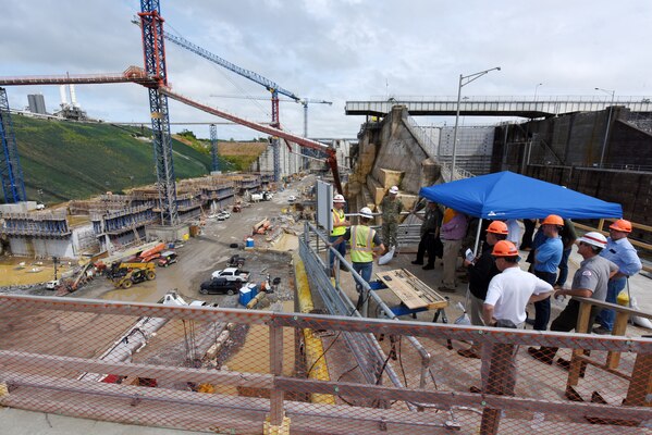 The Inland Waterways Users Board receives a presentation July 19, 2023, about site geology at the Kentucky Lock Addition Project on the Tennessee River in Grand Rivers, Kentucky. The ongoing construction can be seen on the left while the active navigation lock miter gates are visible on the right. The U.S. Army Corps of Engineers Nashville District is constructing a larger lock at the Tennessee Valley Authority dam. (USACE Photo by Lee Roberts)