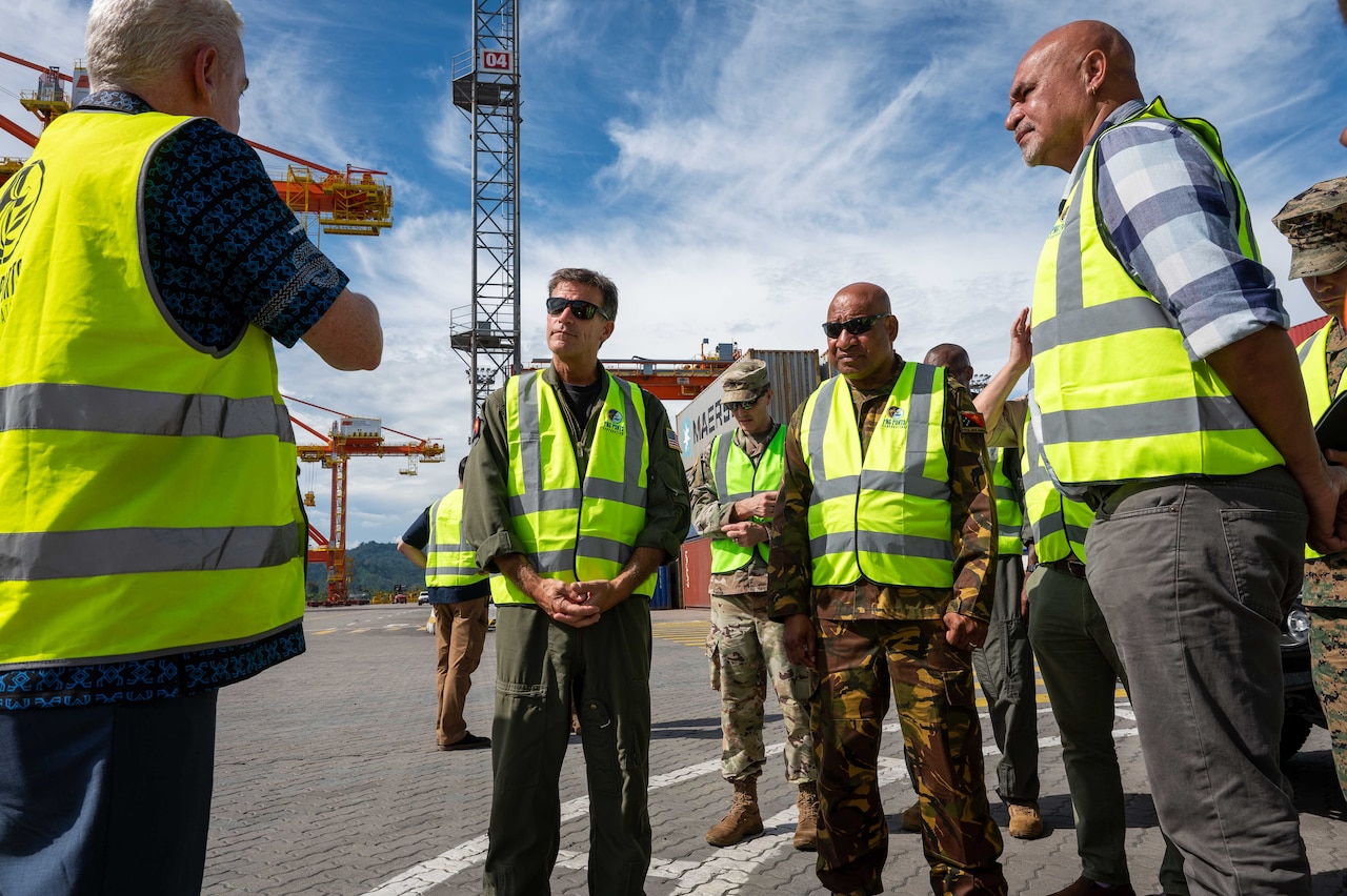 Men with construction vests stand on a working wharf.