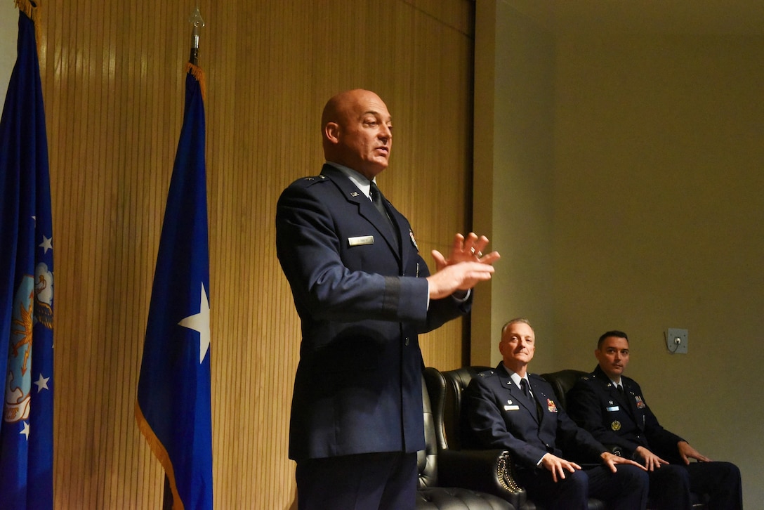 Brig. Gen. George Dietrich III, 82nd Training Wing and Sheppard Air Force Base commander, addresses a small gathering of members of the 982nd Training Group, family and friends during a change of command ceremony at Sheppard Air Force Base, Texas, July 20, 2023. Col. Grant Fowler (seated right), assumed command of the 982nd TRG while Col. Terry Koester (seated left), relinquished command. U.S. Air Force photo by Bailee Russell