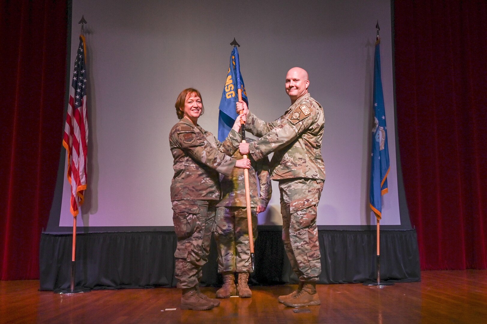 Col. Jeanne Bisesi, 433rd Mission Support Group commander, presents the 433rd Logistic Readiness Squadron guidon to Maj. Jeffrey Barney during an assumption of command ceremony at Joint Base San Antonio-Lackland, Texas, July 9, 2023. The 433rd LRS's mission is to provide the logistical support necessary for the Alamo Wing to complete its assigned missions. (U.S. Air Force photo by Staff Sgt. Adriana Barrientos)