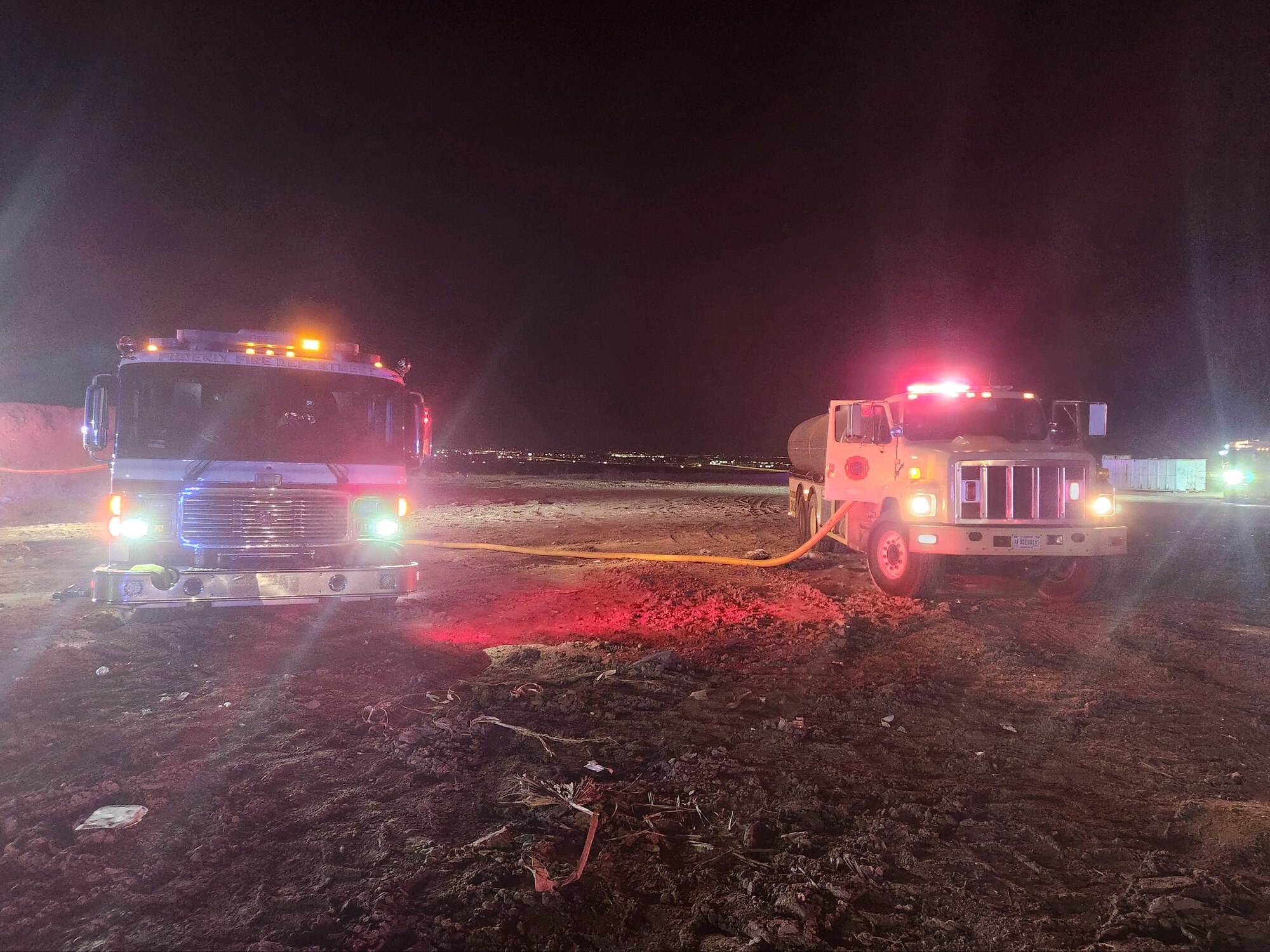 A Phoenix Fire Department firetruck (left) and a Luke Air Force Base Fire Department water tanker (right) respond to a 3-acre fire at the Glendale Municipal Landfill, around 9 p.m., July 19, 2023, in Glendale, Arizona.