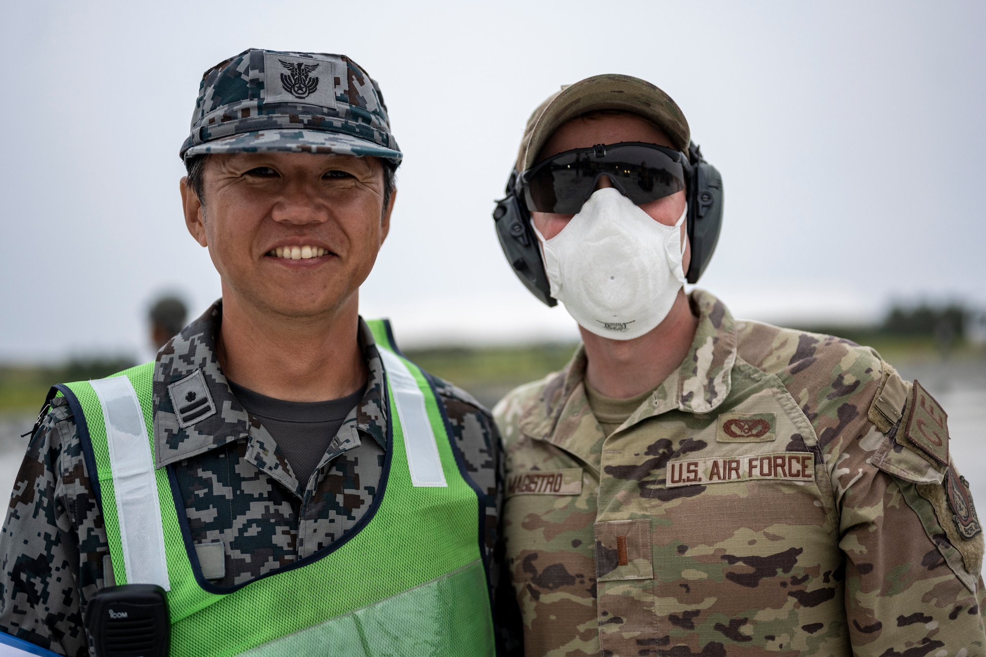 A U.S. Air Force Airman assigned to the 18th Civil Engineer Group and a Japan Air Self-Defense Force Airman assigned to the Western Air Civil Engineering Group pose for a photo during a bilateral live fire exercise.