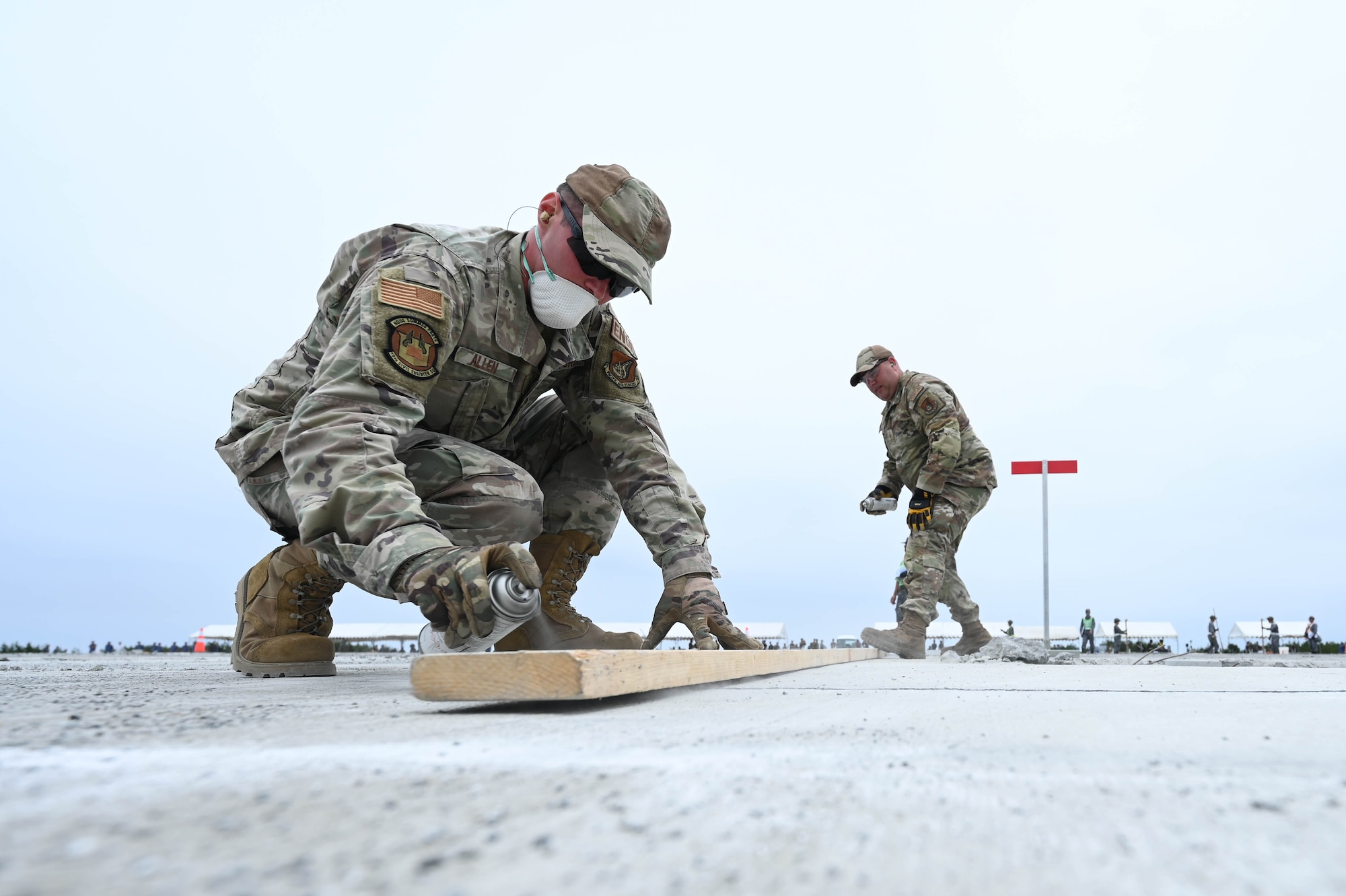 U.S. Air Force Airmen assigned to the 18th Civil Engineer Group use spray paint to outline the area of a rapid airfield damage recovery pad to cut during a bilateral live fire exercise.