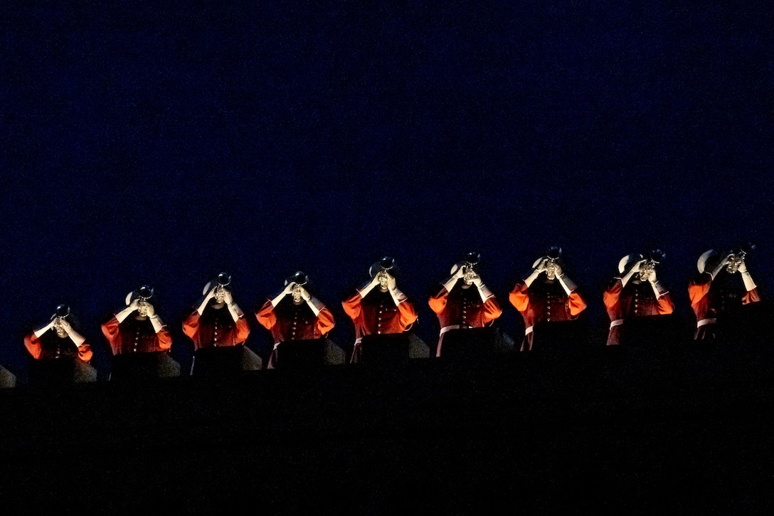 A group of Marines play brass instruments in a dimly lit area.