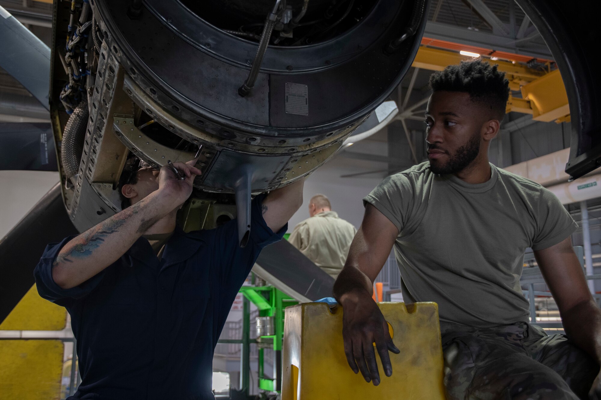 Two men work on an aircraft engine together.