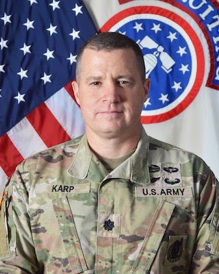 Male Soldier posed in front of the Recruiting Command flag and the United States flag.