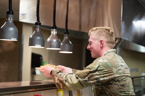 Trainee accepts plate of food from server in line at the dining facility