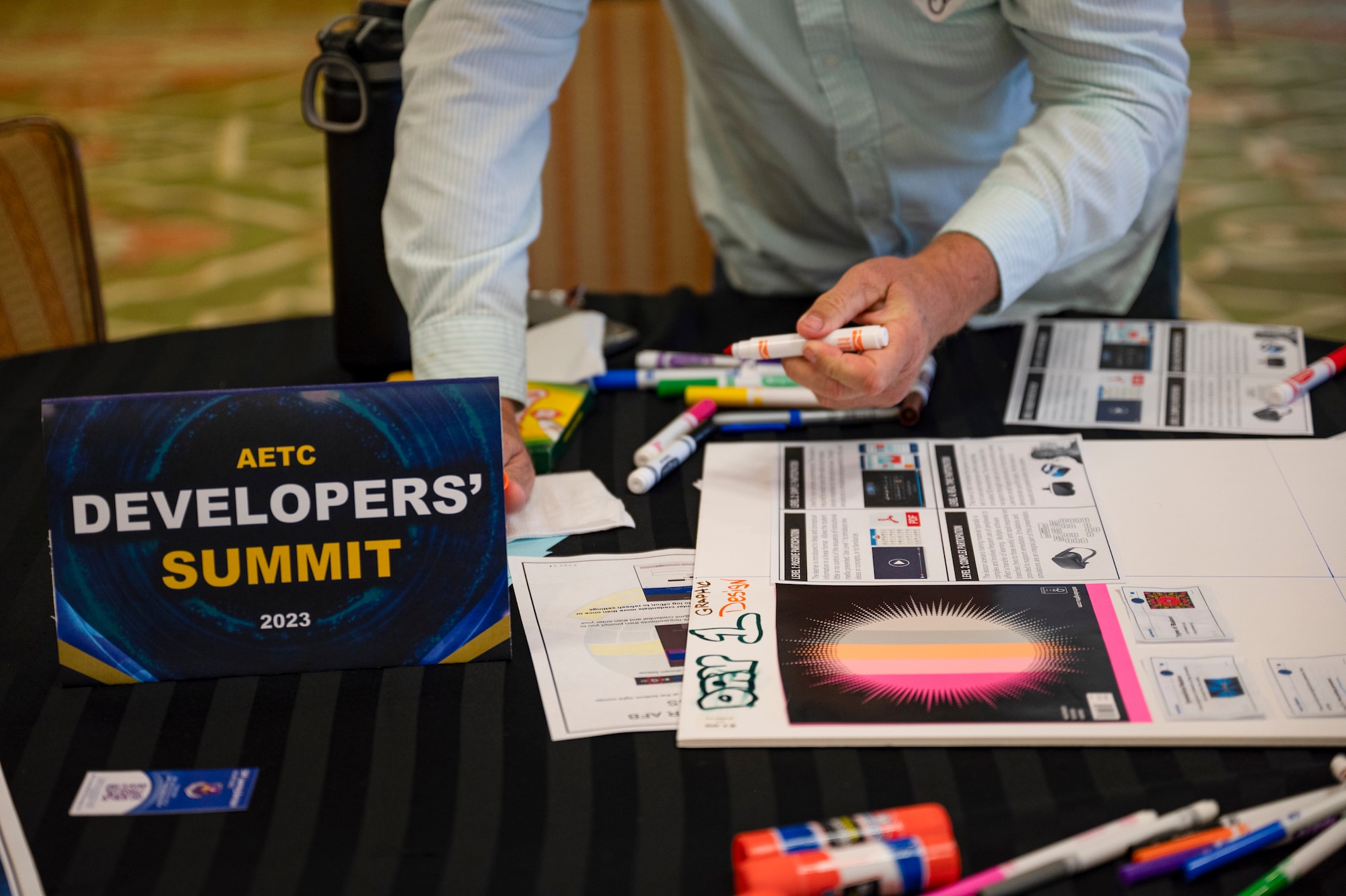 A Developers' Summit participant write on poster with orange marker to build info graphic