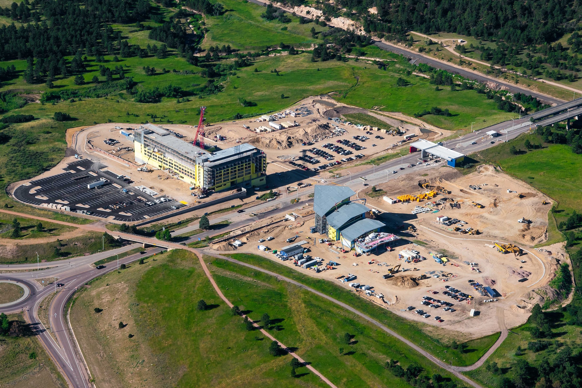 An aerial photo shows two buildings outside of the U.S. Air Force Academy's North Gate. To the right, contractors build a new visitor center that will offer a unique perspective into cadet life.