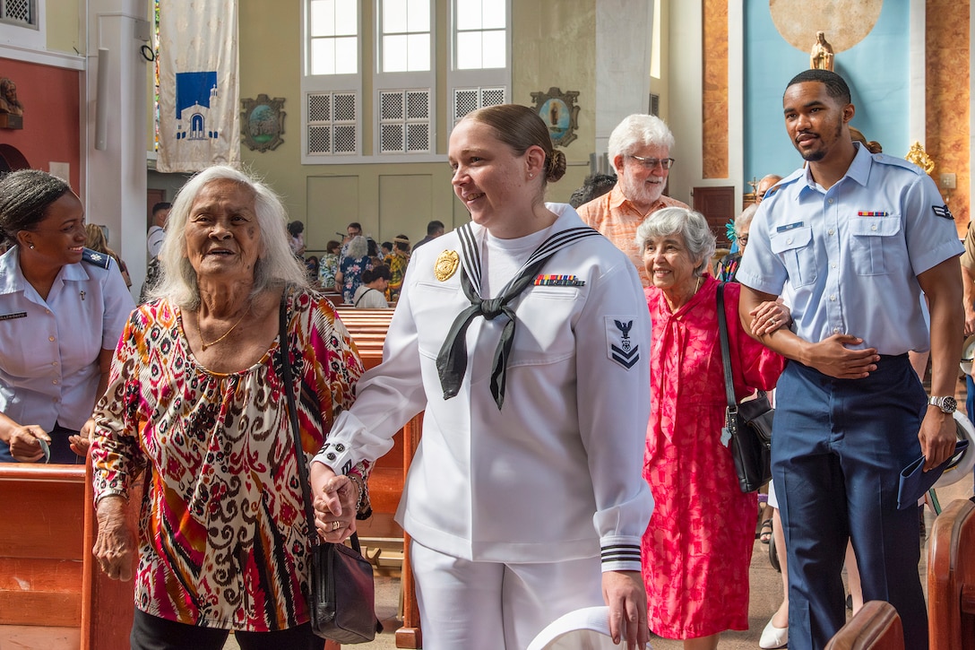 Service members hold hands with community members as they walk in a church.