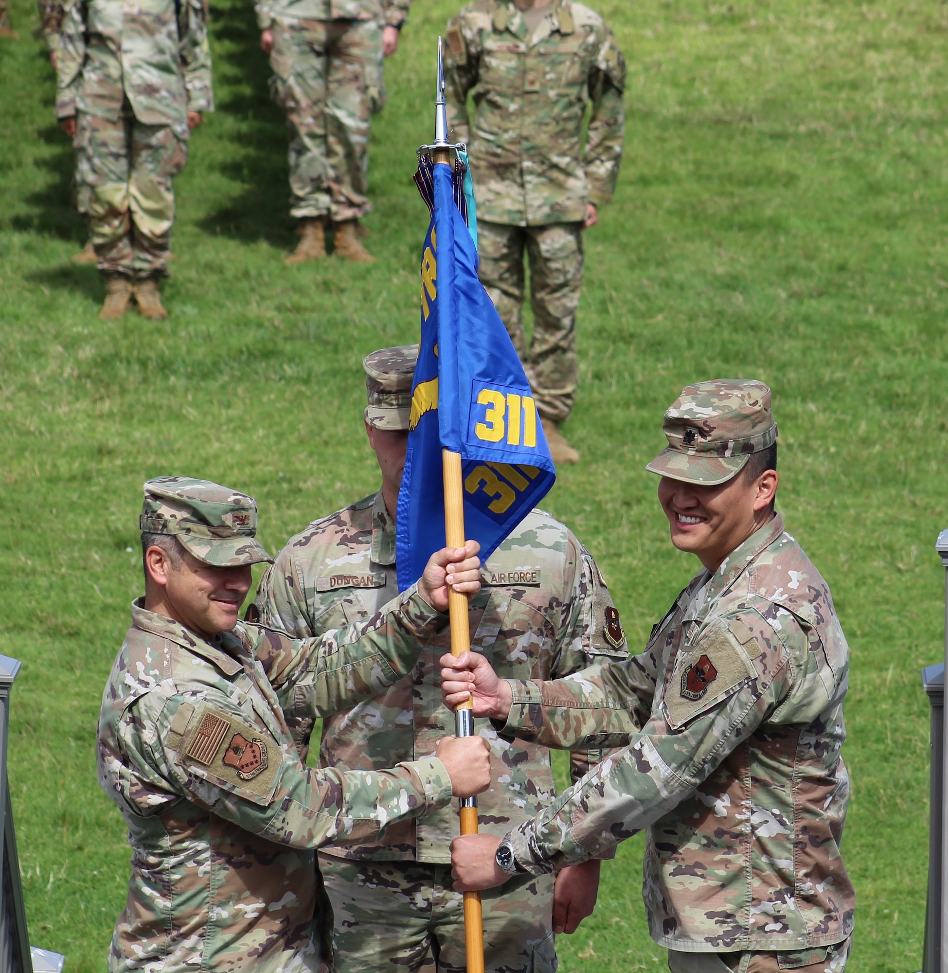 U.S. Air Force Col. Mark Jones, 517th Training Group commander, passes the guidon to Lt. Col. Chin Tam incoming 311th Training Squadron commander, during the 311th TRS change of command ceremony on Soldier Field at the Presidio of Monterey, California, July 6, 2023. Tam was previously the Director of Operations for 313th Training Squadron at Goodfellow Air Force Base, Texas. (U.S. Air Force photo by Tech. Sgt. Alexandria Holder)