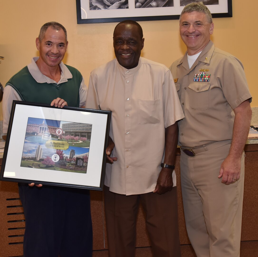 James Martin (left) presenting photographic montage to U.S. Army (Ret.) Floyd Atwater (center) while U.S. Navy Capt. David Lang recognizes Walter Reed’s longest-serving employee.