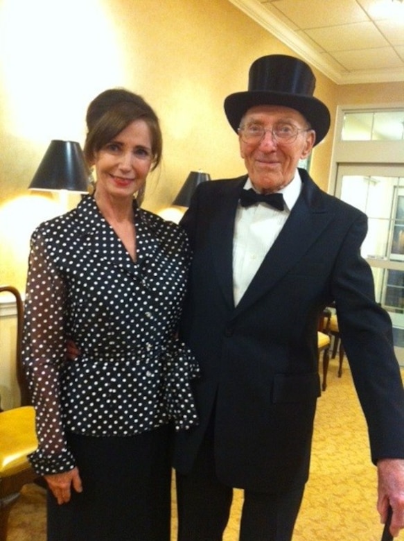 A man in a top hat, tuxedo and bowtie poses with a woman.