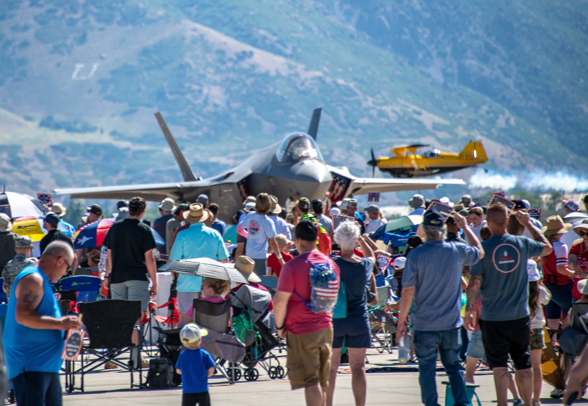 People watching an Air Force jet on the ground and a civilian jet in the air