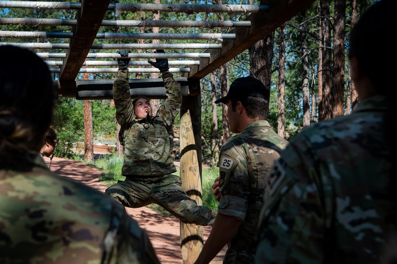 A cadet moves through an obstacle as others watch.