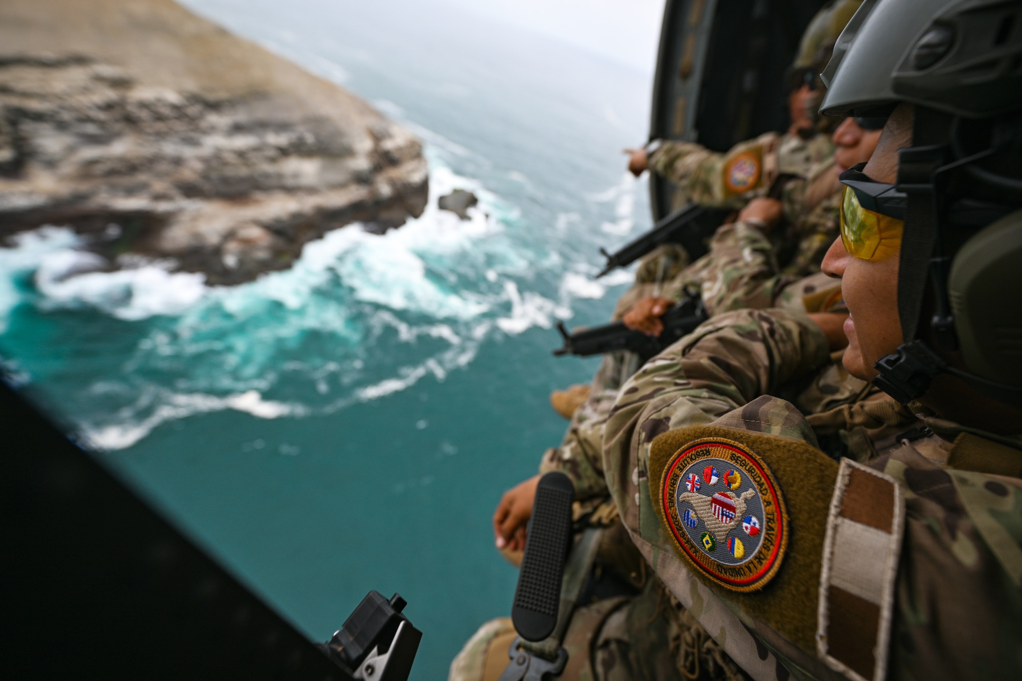 Airmen sit in an aircraft and overlook the sea below