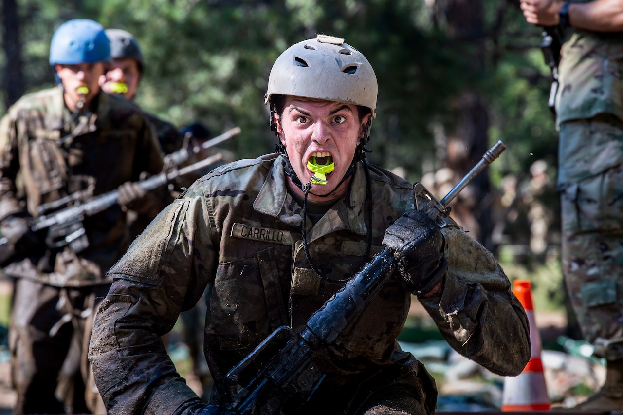 A cadet runs with a weapon while grimacing.