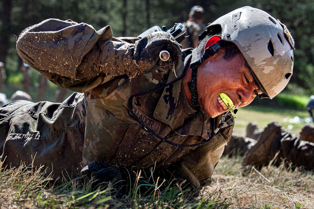 A cadet crawls while holding onto a weapon.